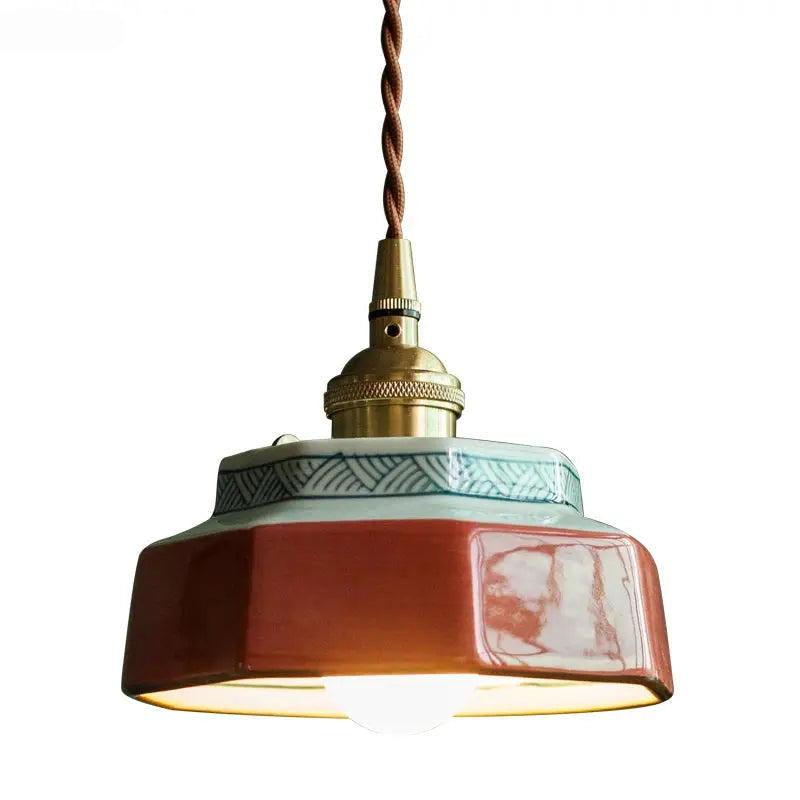 Decorative pendant light with ceramic shade and brass fitting on a white background