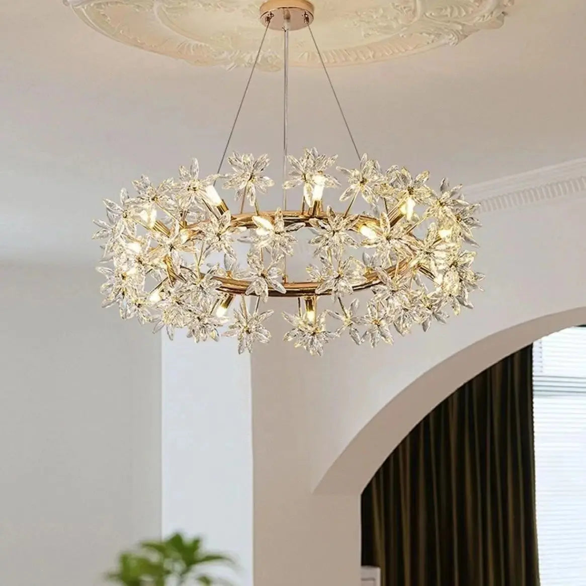 Chandelier with crystal accents hanging in a room with a decorative ceiling.