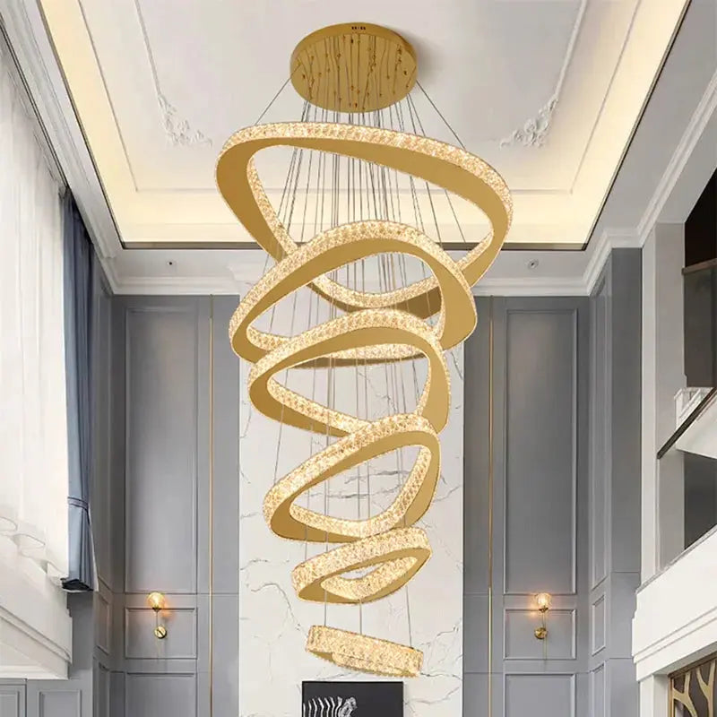 Gold spiral chandelier hanging in a modern interior setting with gray walls and white ceiling.