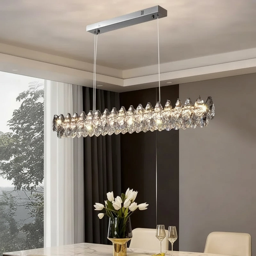 Modern chandelier hanging in a dining room with a window and table setting.